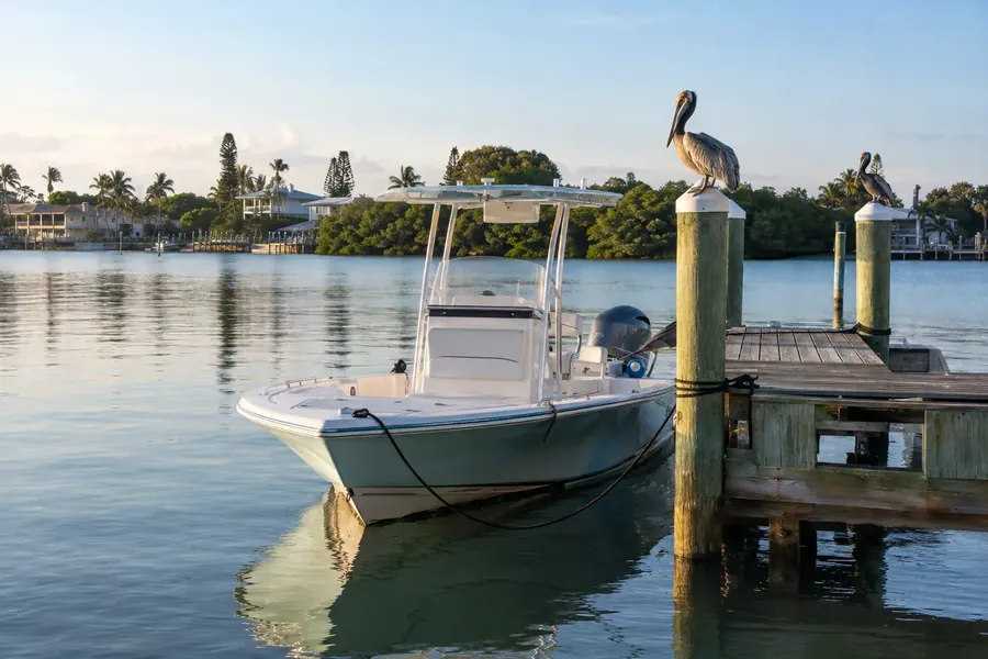 Bay boat tied at a wooden dock in St. Petersburg with pelicans on the pilings