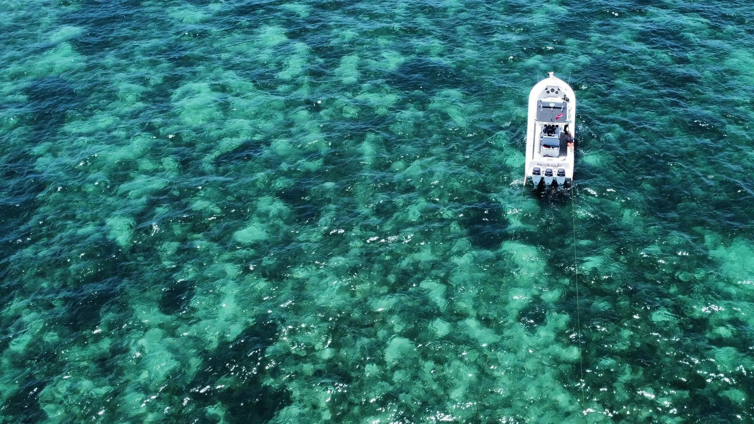 Drone view of a white center-console boat over turquoise shallows