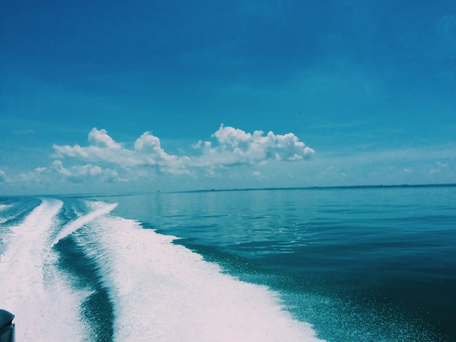 Boat wake across turquoise water under a blue sky