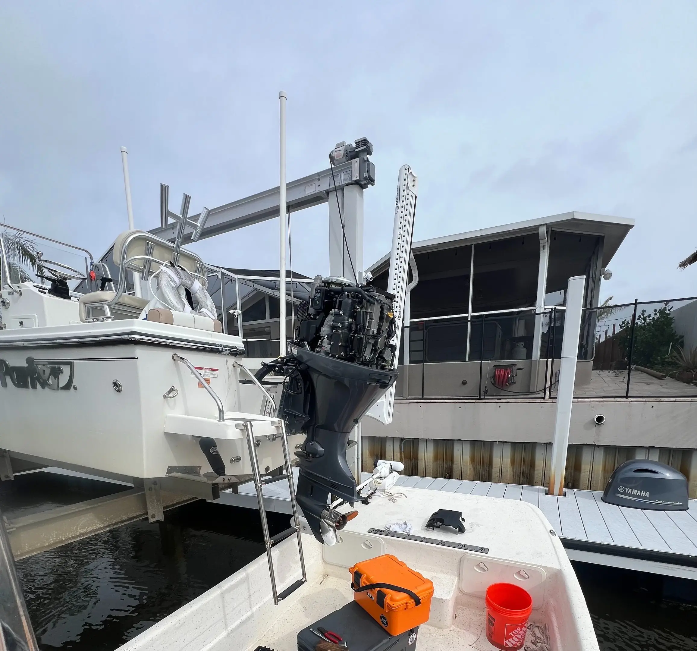Skiff on a boat lift with a Power-Pole anchor and the outboard cowling off for service